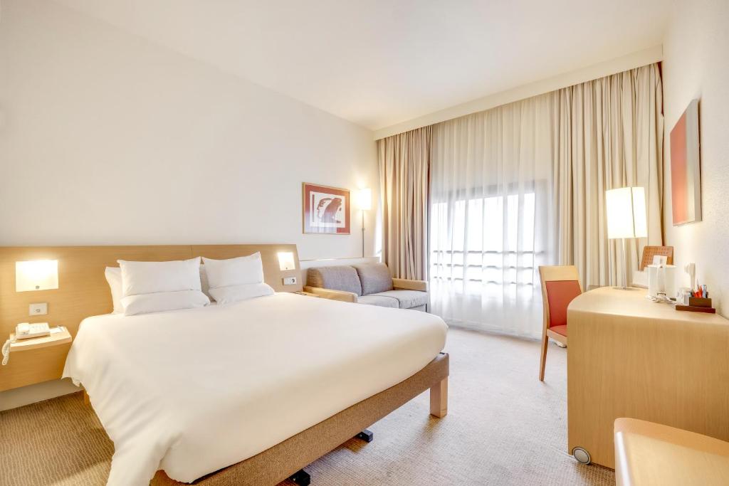 ベルフォールにあるノボテル ベルフォール サントル アトリアの大きなベッドと椅子が備わるホテルルームです。
