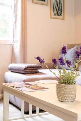 a room with a table with a vase with purple flowers on it at Quartz Cottage Geelong in Geelong