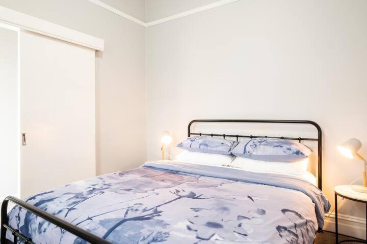 a bedroom with a bed with a blue and white comforter at Quartz Cottage Geelong in Geelong