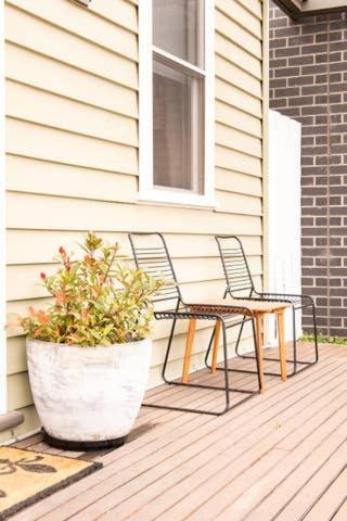 two chairs and a table and a potted plant on a porch at Quartz Cottage Geelong in Geelong