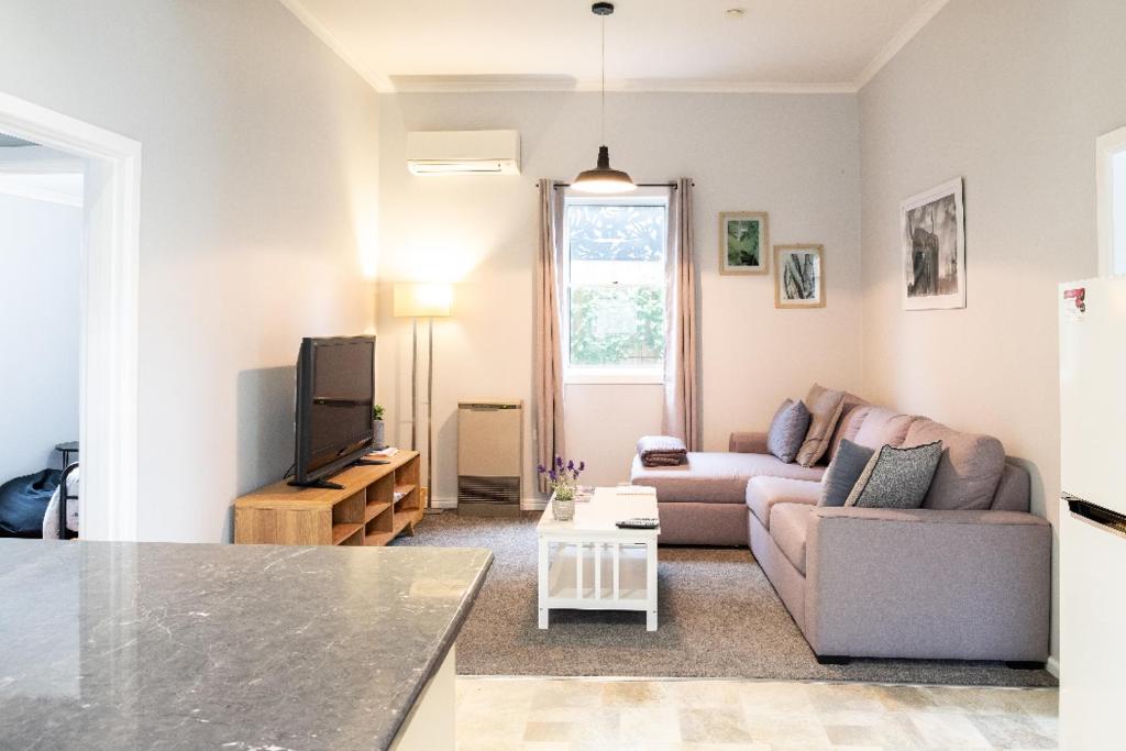 a living room with a couch and a tv at Quartz Cottage Geelong in Geelong
