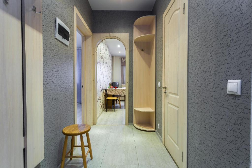 a hallway with a table and a stool in a room at Apartment on Glukharskaya near MIBS in Saint Petersburg