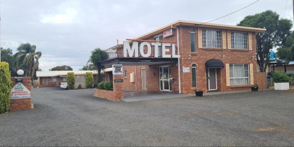 Un motel de ladrillo con un cartel en la parte delantera en Alfa motel en Gilgandra