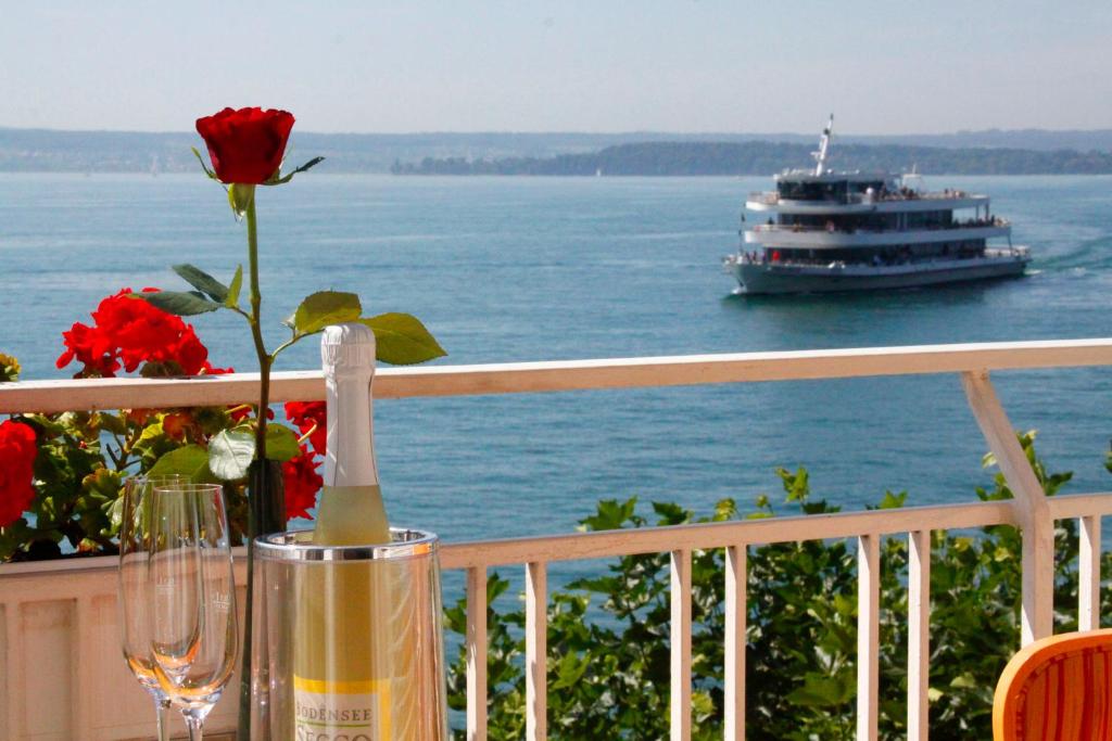 a table with a flower and a boat in the water at Seehotel ZUR MÜNZ in Meersburg