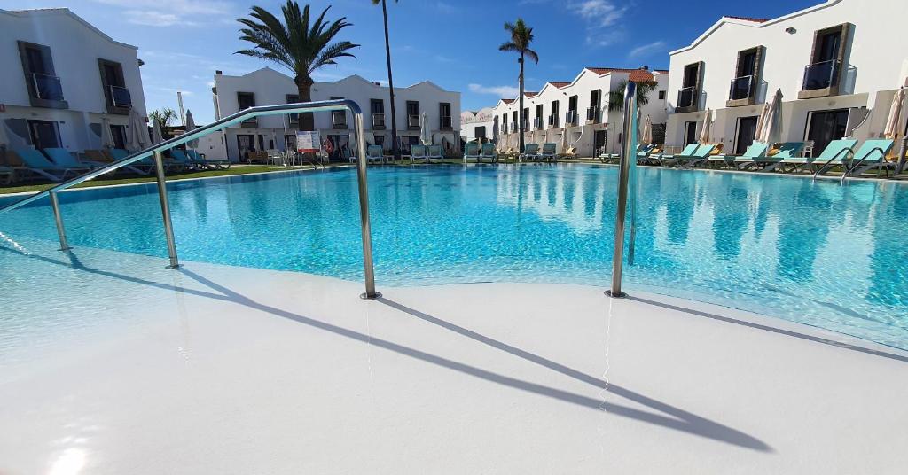 una gran piscina con sillas y edificios en FBC Fortuny Resort - Adults Only, en Maspalomas