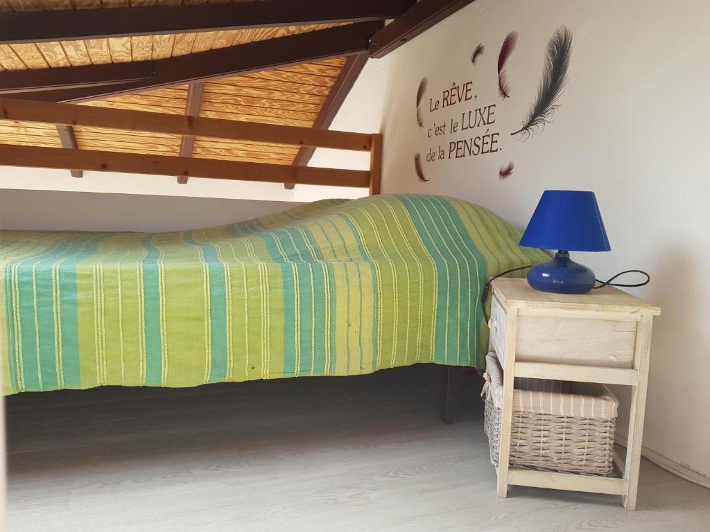 Schlafzimmer mit einem Bett und einer blauen Lampe auf dem Tisch in der Unterkunft Les Gites L'archipel - gite Les Saintes in Saint-Claude