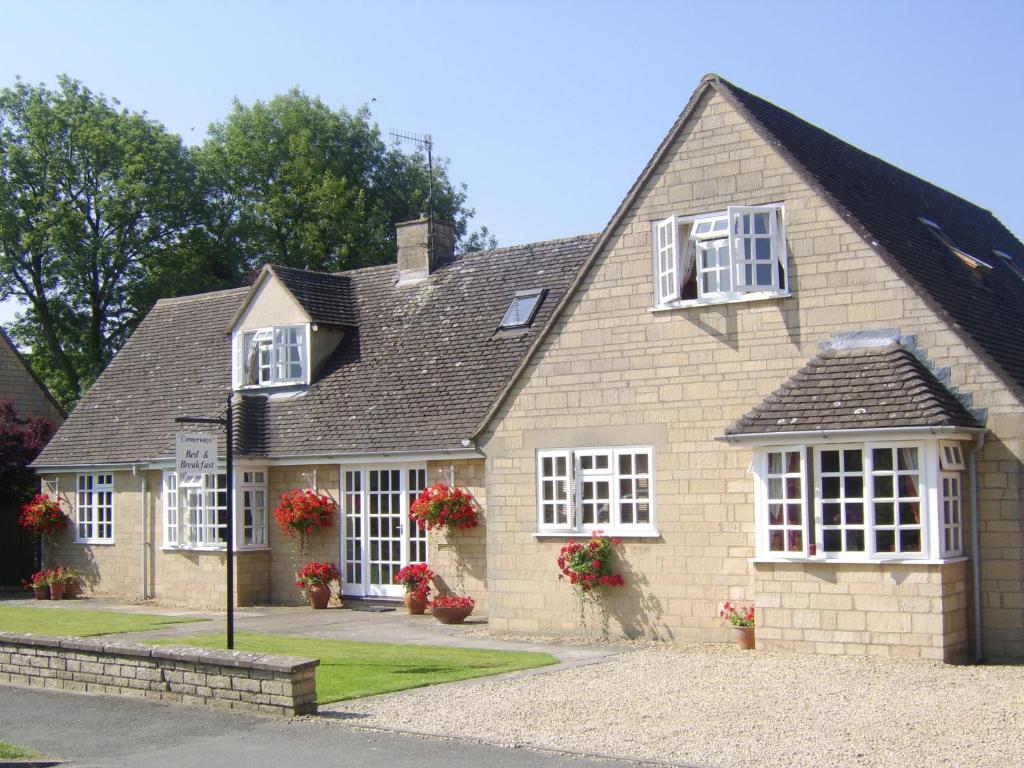 a house with white windows and red flowers on it at Cornerways B&B in Chipping Campden