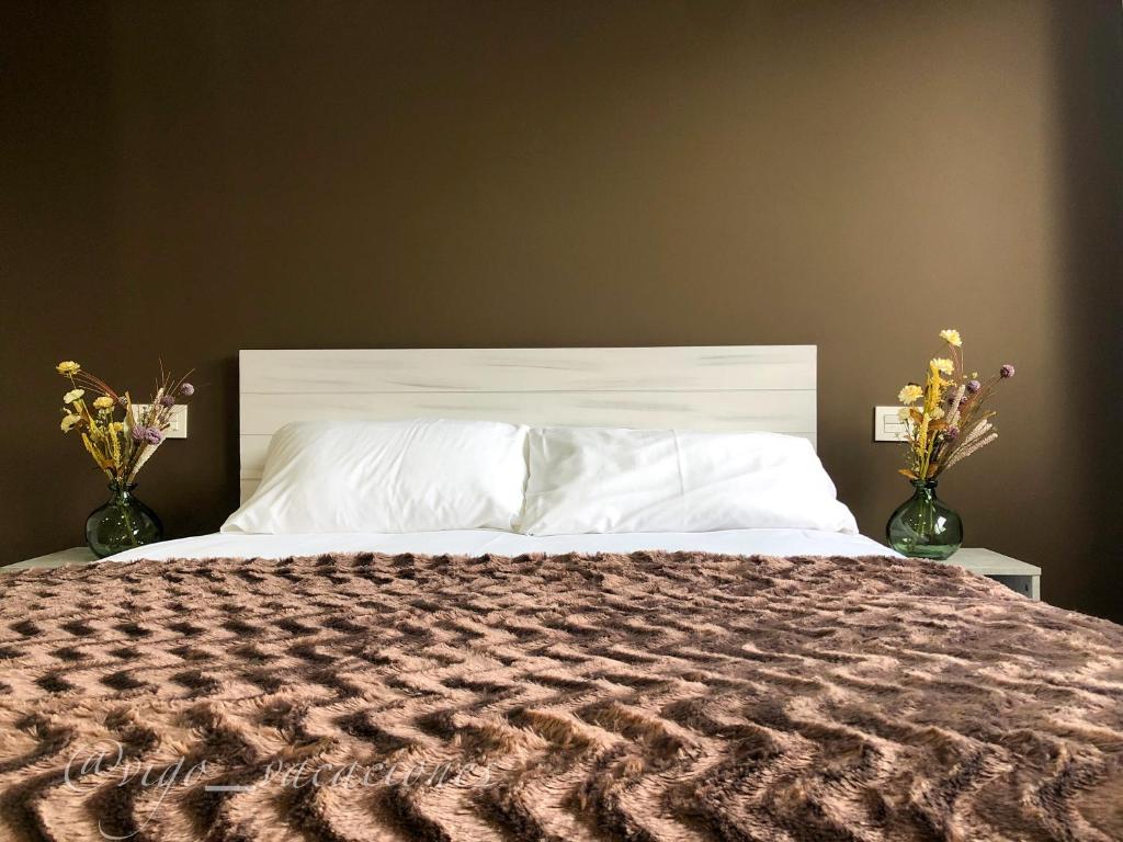 a bedroom with a large bed with two vases with flowers at Pizarro55 By Vigovacaciones in Vigo