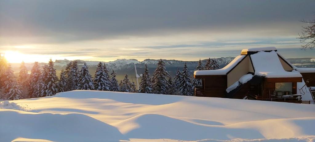 a house covered in snow with the sun in the background at Appartement d&#39;une chambre avec vue sur la ville balcon et wifi a Chamrousse in Chamrousse