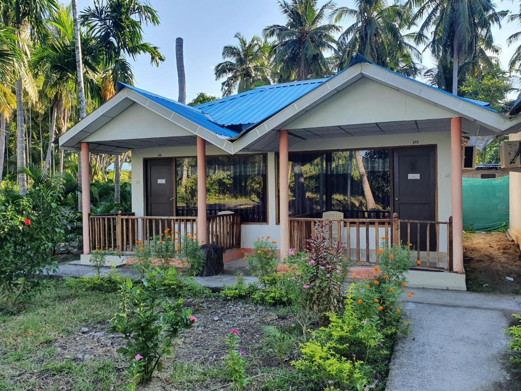 a small house with a porch with a blue roof at Blue Lagoon Resort, Neil Island in Neil Island