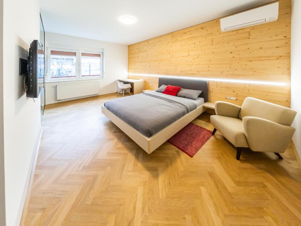 ein Schlafzimmer mit einem Bett, einem Sofa und einem Stuhl in der Unterkunft Kamr’ca in Ljubljana