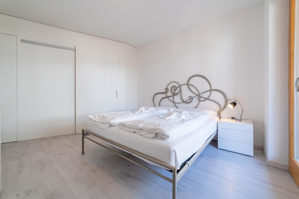 biała sypialnia z łóżkiem z metalowym zagłówkiem w obiekcie Olivia Home w mieście Caprile