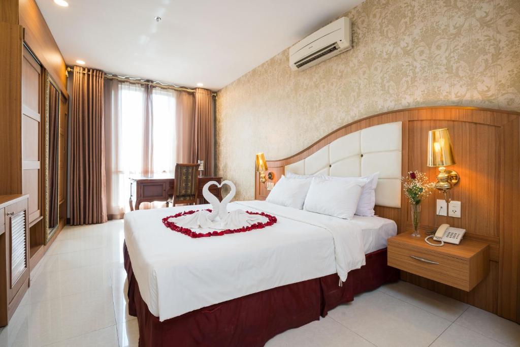 ein Schlafzimmer mit einem großen weißen Bett mit einer roten Blume darauf in der Unterkunft Lam Kinh Hotel in Ho-Chi-Minh-Stadt