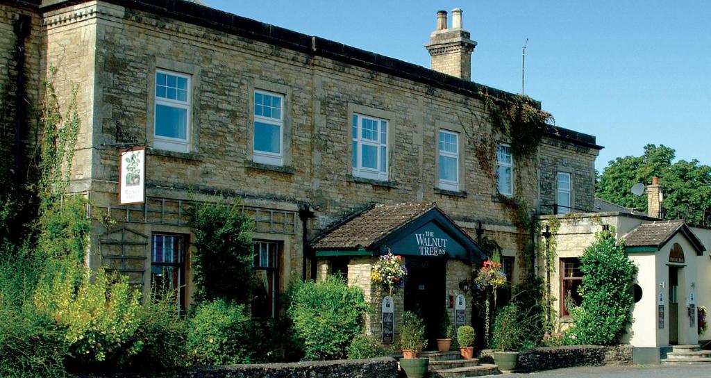 um velho edifício de tijolos com uma placa em frente em The Walnut Tree Inn em Northampton