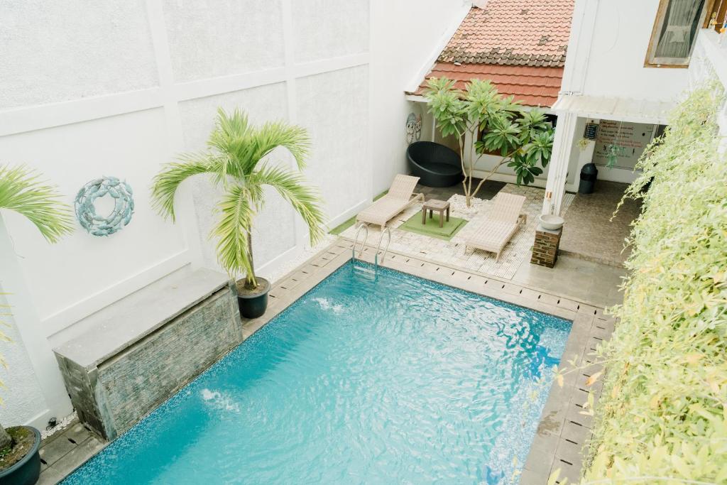 a swimming pool with two palm trees and a house at Otu Hostel By Ostic in Yogyakarta