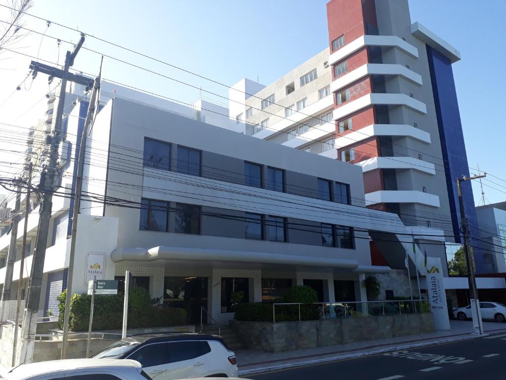 a white car parked in front of a building at Atalaia Apart Hotel in Aracaju