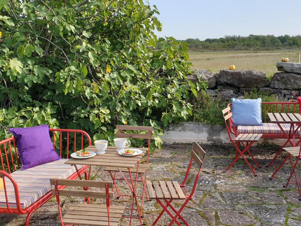 ein Holztisch mit Stühlen und ein Tisch mit Teller mit Lebensmitteln darauf in der Unterkunft Marsjö Gård Bo & Yoga vandrarhem in Borgholm