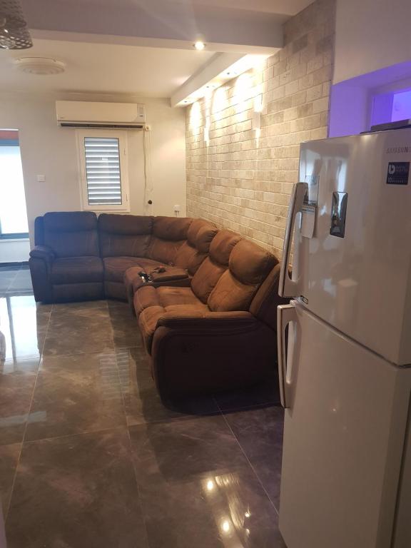 um sofá castanho numa sala de estar com um frigorífico em menny's kinneret דירת כינרת em Tiberias