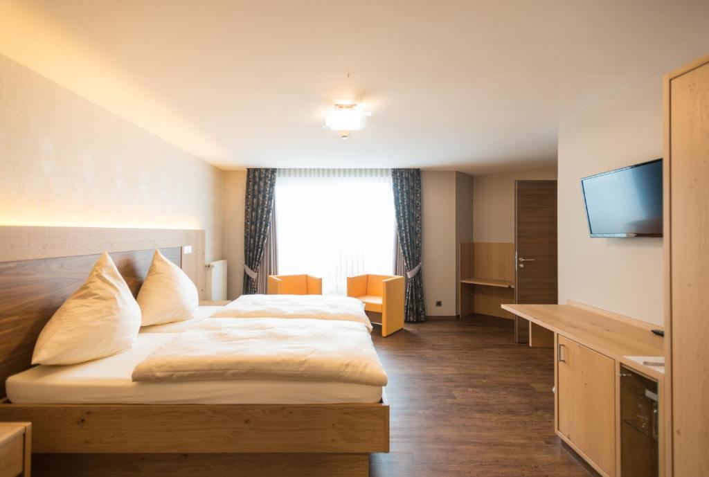 a hotel room with a bed and a flat screen tv at Hotel Haus Tiefenbach in Bullange