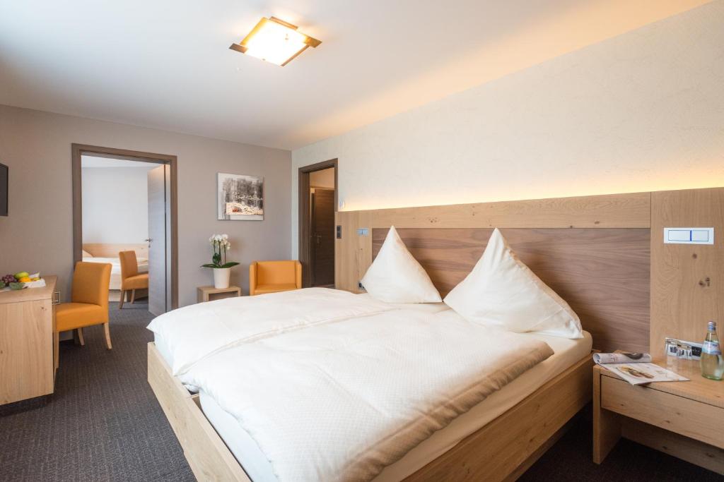 a bedroom with a large white bed and a desk at Hotel Haus Tiefenbach in Bullange
