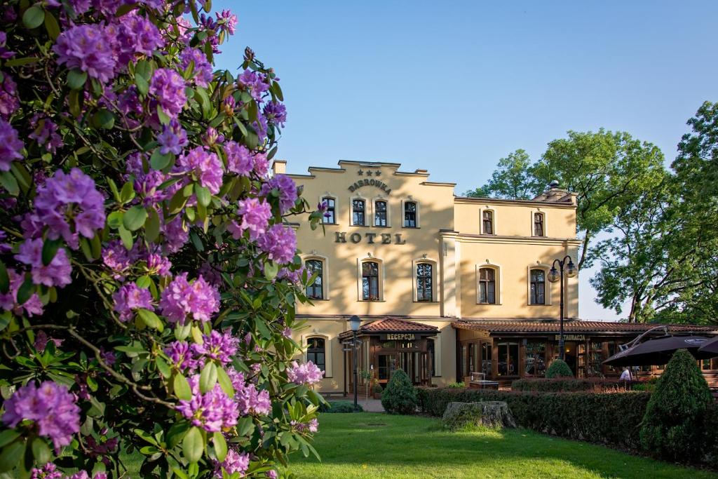 un edificio con flores púrpuras delante de él en Kompleks Dąbrówka, en Jastrzębie-Zdrój