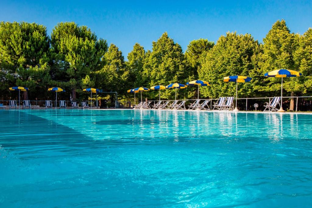 una piscina con agua azul y sombrillas en Country House UNA, en Cupra Marittima