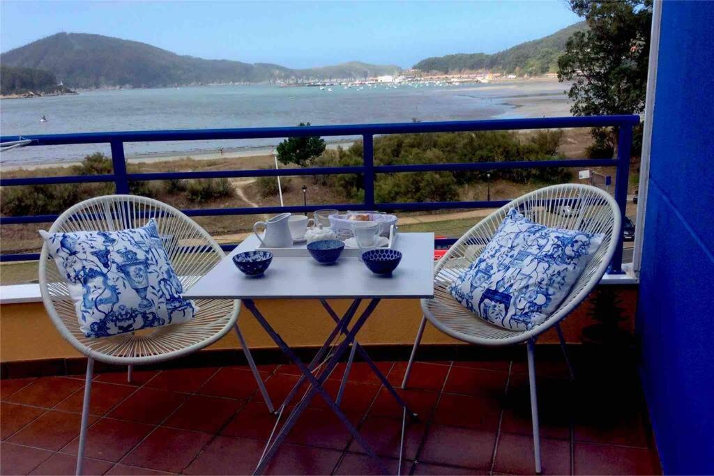 einen Tisch und zwei Stühle auf einem Balkon mit Strand in der Unterkunft Mar azul en puerto azul in Cedeira