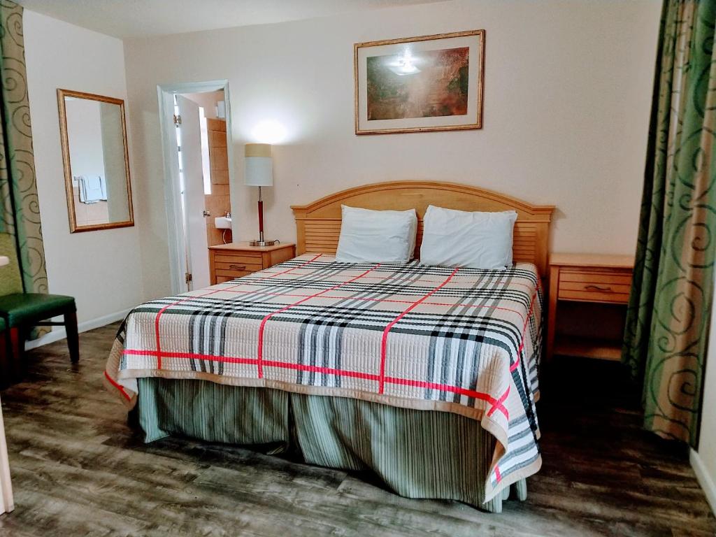 a bedroom with a bed with a checkered blanket at Travelers Inn - Clearwater in Clearwater