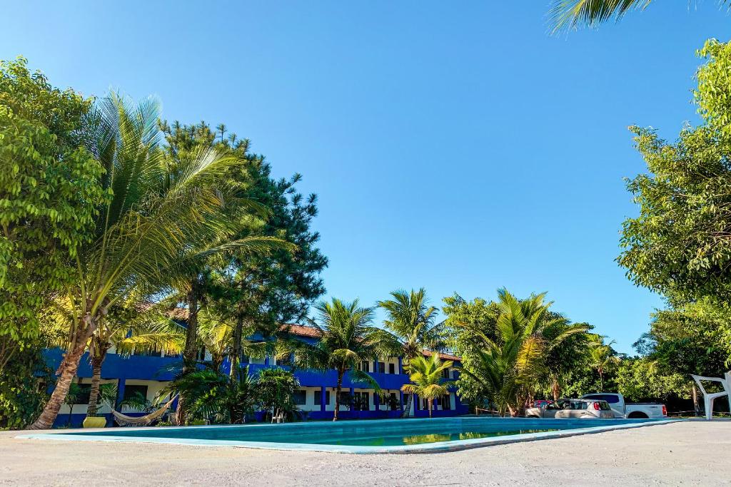 a resort with a swimming pool with palm trees at Pousada Migo in Porto Seguro