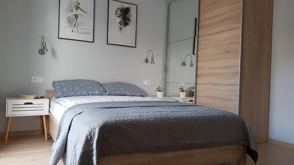 a bedroom with a bed and a white wall at Apartament przy Onkologii in Bydgoszcz