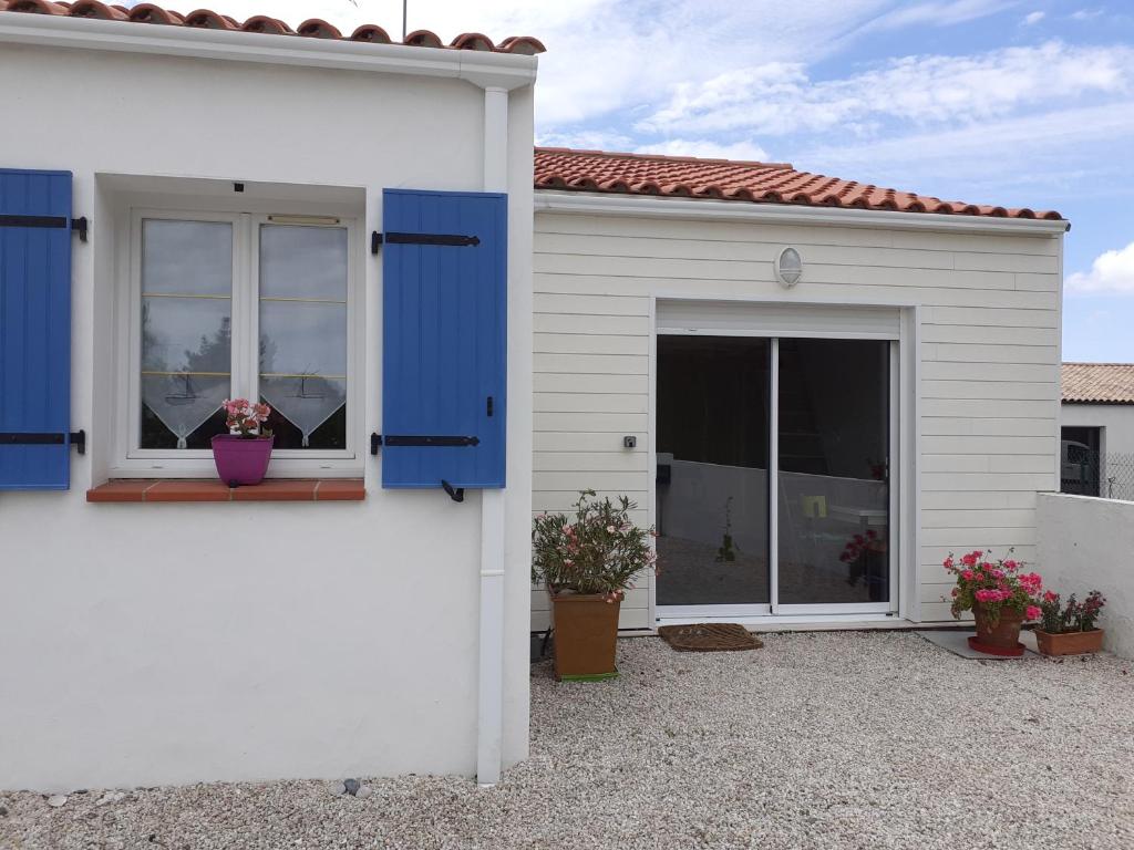 ein weißes Haus mit blauen Fensterläden und einem Fenster in der Unterkunft studio lumineux dans la coulée verte à Saint gilles croix de vie in Saint-Gilles-Croix-de-Vie