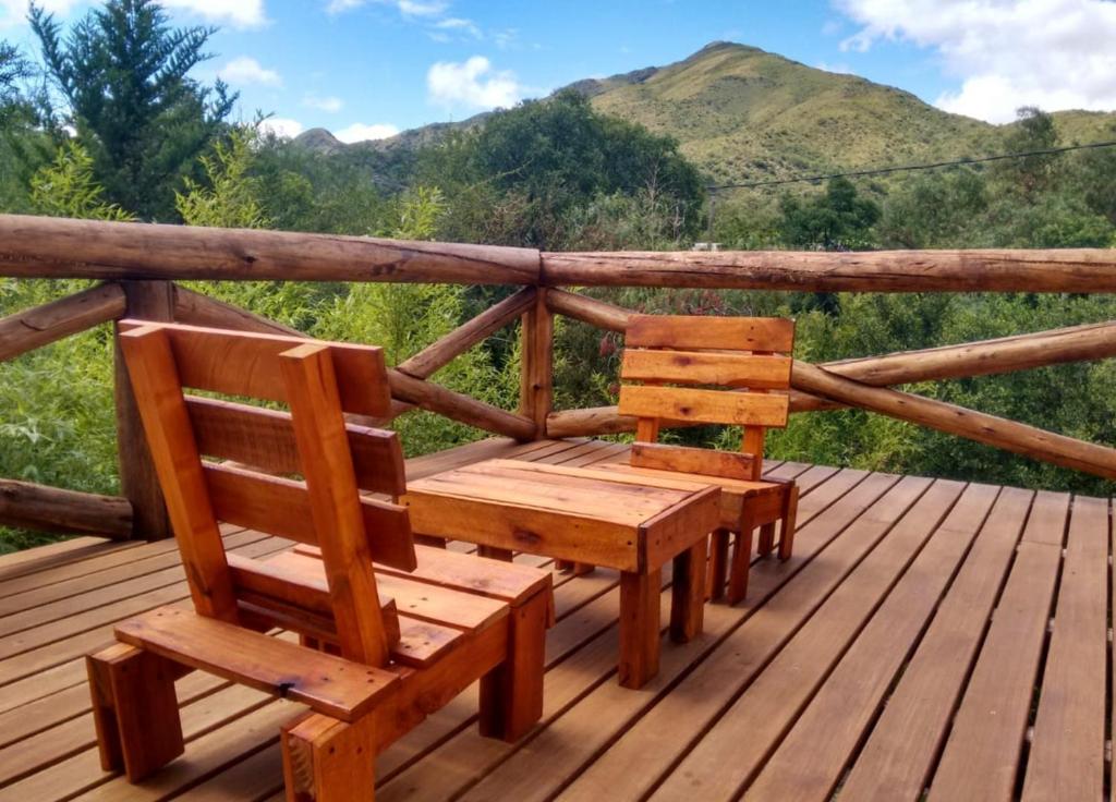 two wooden benches sitting on a deck with mountains in the background at Casa La Toma in Capilla del Monte