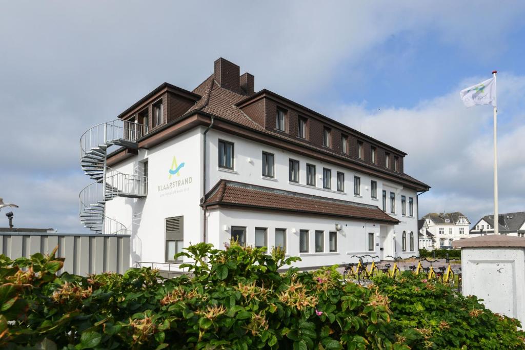 a white building with a brown roof at Haus Klaarstrand in Wenningstedt