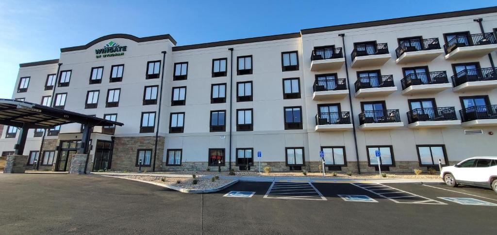 ein großes weißes Gebäude mit einem Auto auf einem Parkplatz in der Unterkunft Wingate by Wyndham Page Lake Powell in Page