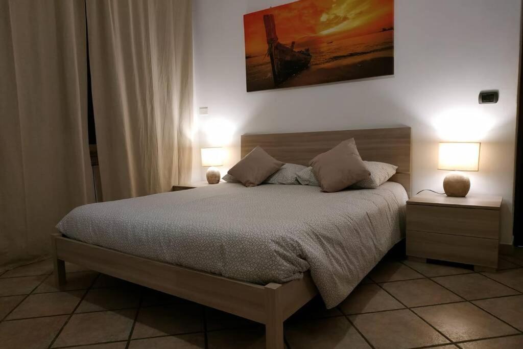 een slaapkamer met een bed met 2 nachtkastjes en 2 lampen bij Camera confortevole tra Roma e Ostia in Acilia