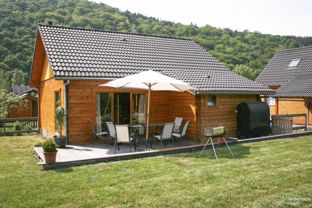 een houten hut met een tafel en stoelen en een parasol bij Chalet Val de l'Amblève in Sougné-Remouchamps