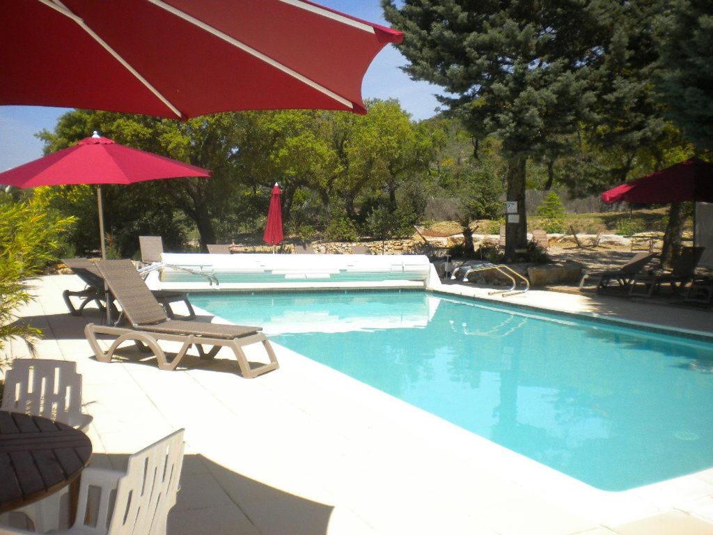 a swimming pool with two chairs and an umbrella at Le Mas Saint Donat in Sainte-Maxime