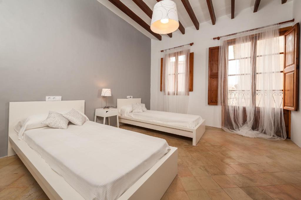 a white bedroom with two beds and a window at CA NA BLANCA in Alcudia