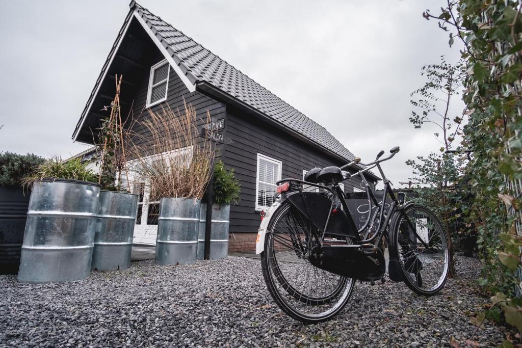 een fiets geparkeerd voor een zwart huis bij Je B&B Giethoorn, incl fietsen! in Giethoorn