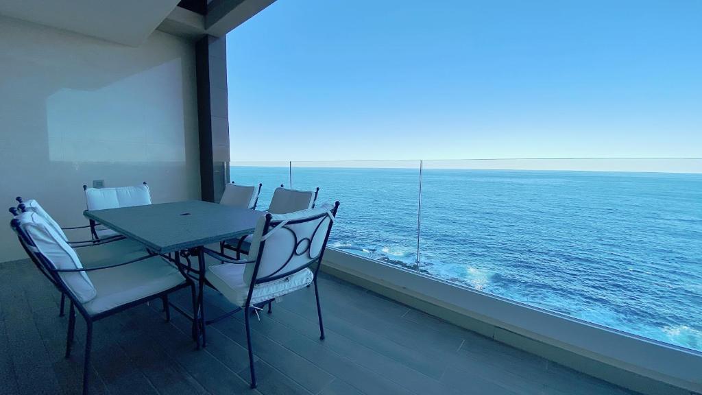 een tafel en stoelen op een balkon met uitzicht op de oceaan bij Quisisana Apartments - Cast Renting in Sliema