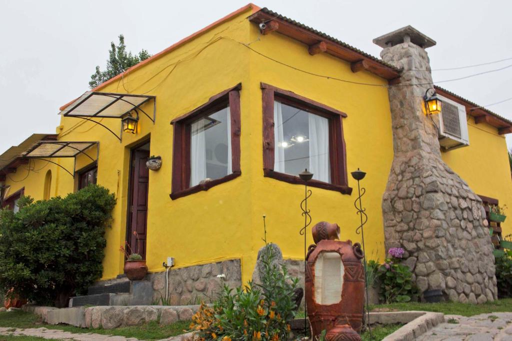 a yellow house with a stone wall at Cabañas del Sol in Tafí del Valle