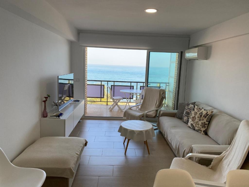 een woonkamer met een bank en uitzicht op de oceaan bij Ático en primerísima linea de playa!!! in Denia