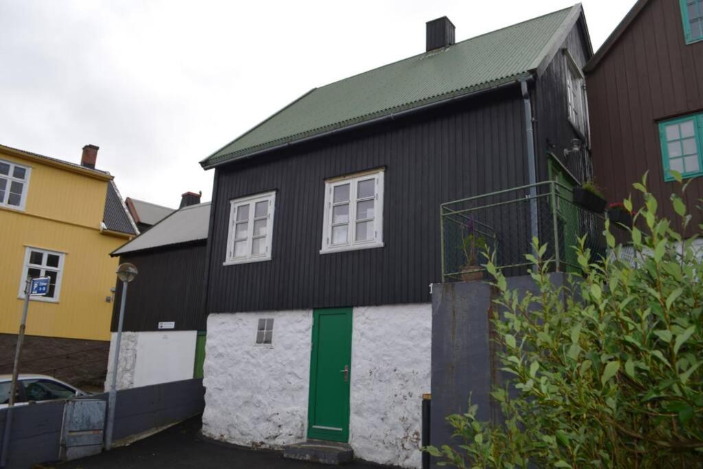 una casa nera con una porta verde sul lato. di Cosy house in the heart of Tórshavn (Á Reyni) a Tórshavn