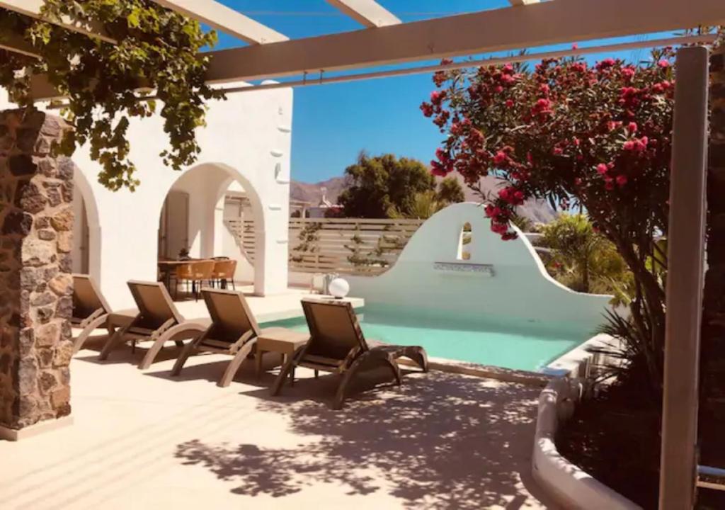 a patio with chairs and a table next to a pool at DAFNES VILLA 1 Private Pool in Perivolos