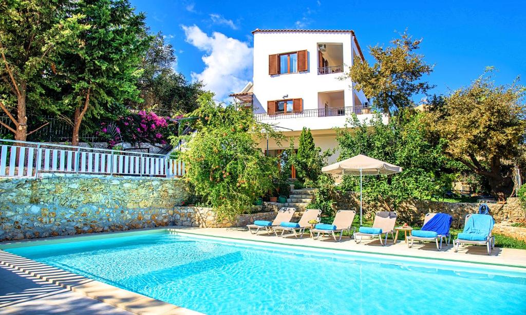 a villa with a swimming pool and chairs and a house at Grand View Villa Private Heated Pool in Georgioupoli