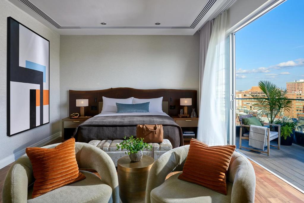 a bedroom with a bed and two chairs and a balcony at The Dupont Circle Hotel in Washington, D.C.