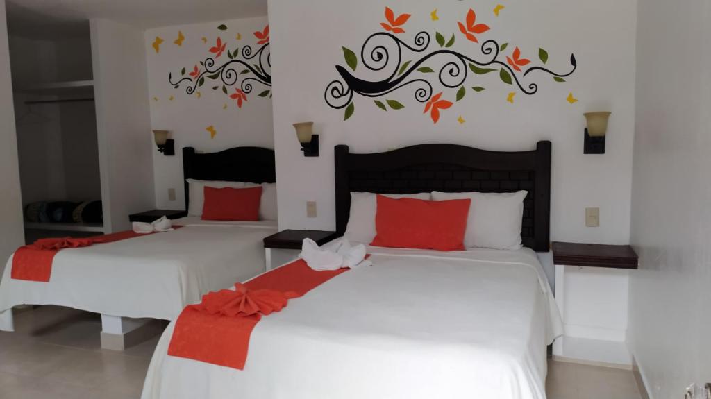 a bedroom with two beds with red pillows at Hotel Posada Las Casas in San Cristóbal de Las Casas