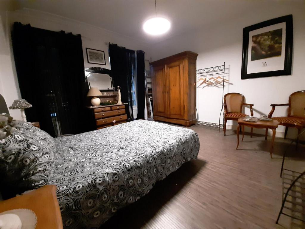 een slaapkamer met een bed, een dressoir en stoelen bij Les Clefs de la Liberté in Colmar