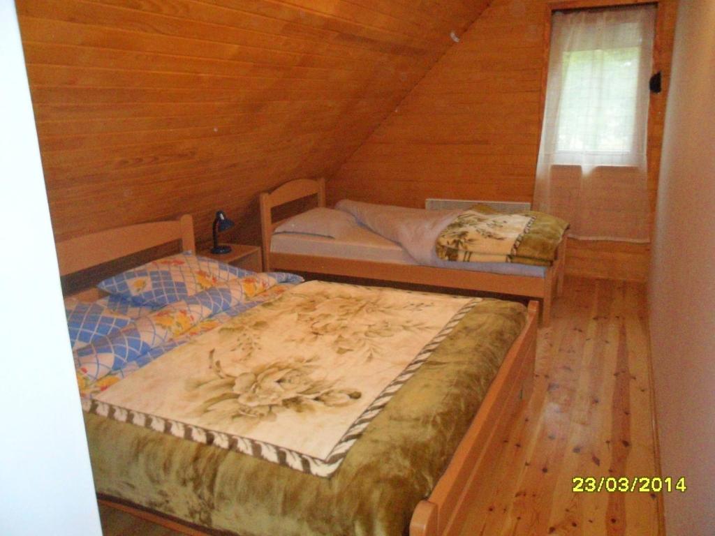 two beds in a room with a wooden ceiling at Apartments Sara in Žabljak