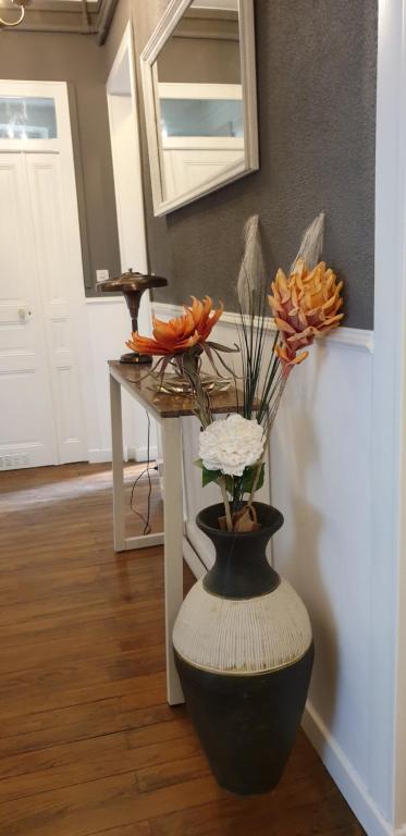 un vase avec des fleurs dans une pièce avec une table dans l'établissement L Hôte Rutène, à Rodez